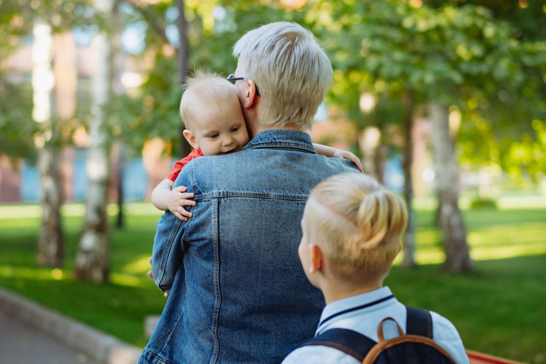 rentrée scolaire avec un bébé dans les bras de maman